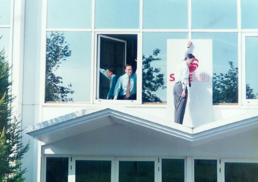 Txetxu Fernández Bilbao observa desde la ventana como Roberto Beitia Bastida coloca un cartel provisional con el nuevo nombre de la empresa.